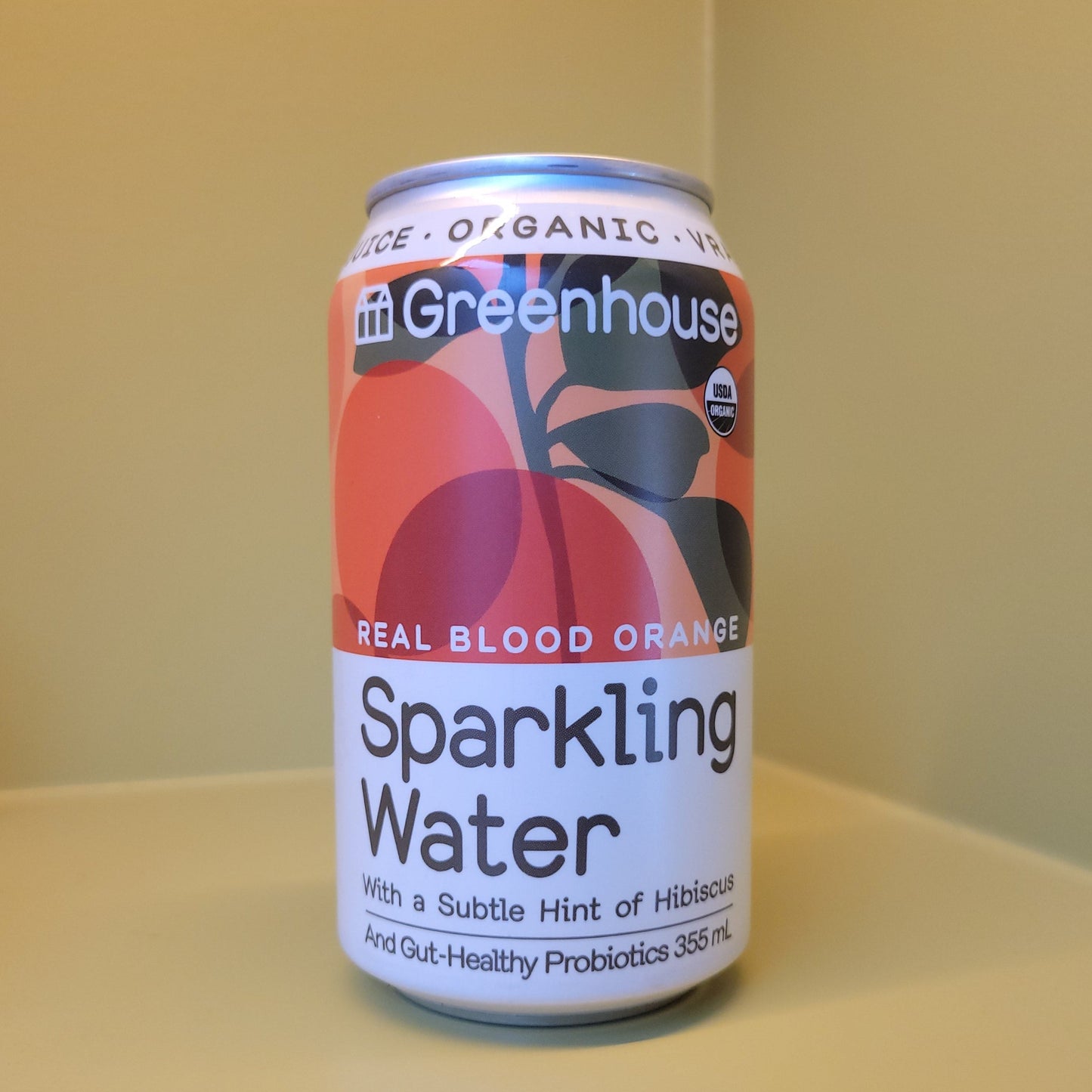 Can of Greenhouse Organic Blood Orange Sparkling Water on a yellow background